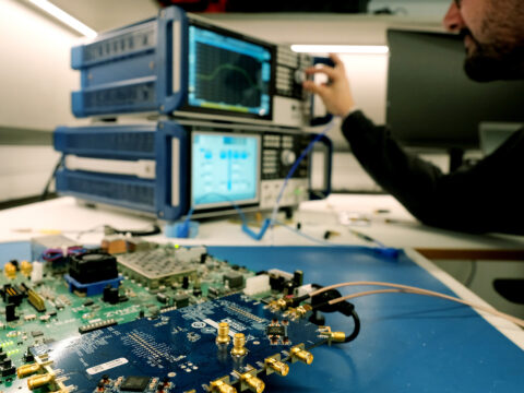 Fotografia d'una placa electrònica i uns monitors de seguiment de satèl·lits. Puig, A. (2025). I-CERCA.